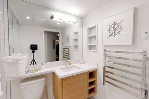 Ein modernes Badezimmer mit einem weißen Waschbecken, einer Holzausstattung und einem großen Spiegel.