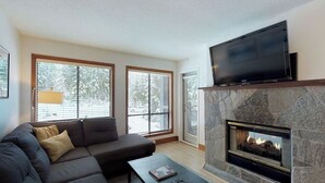 Una sala de estar moderna con chimenea de piedra, un televisor de pantalla plana grande y un sofá modular.