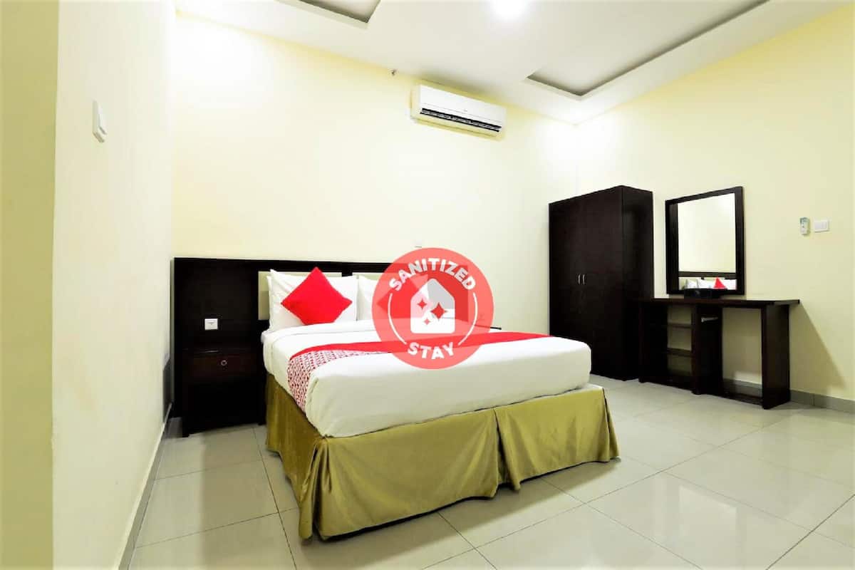Una habitación de hotel con cama, mesita de noche, armario, espejo y aire acondicionado.
