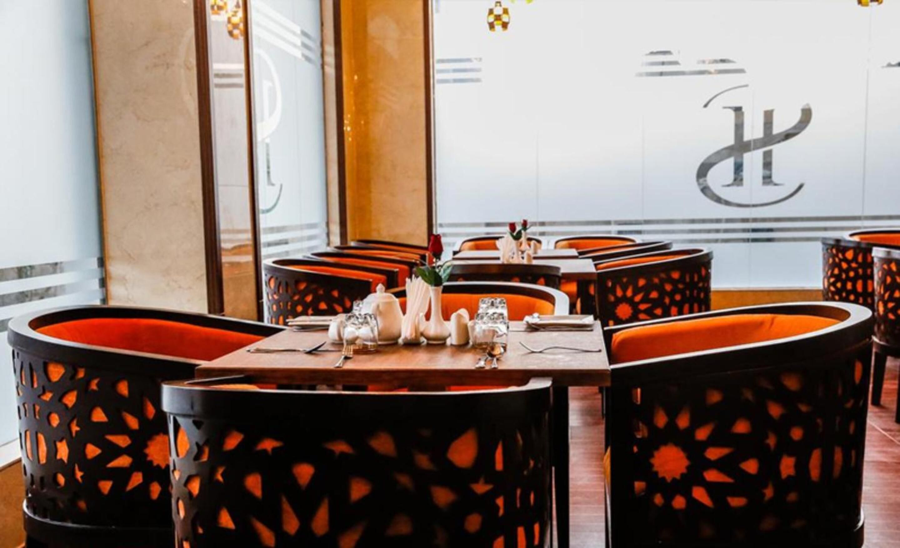 Een restaurantinterieur met zitjes, gedekte tafels en een groot logo op de muur.