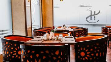 Een restaurantinterieur met zitjes, gedekte tafels en een groot logo op de muur.