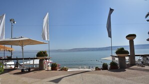 A terrace with a view of the sea, featuring umbrellas, potted plants, and flags. - The Kings Towers (Tiberias)