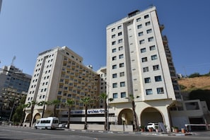 A multi-story hotel with a modern design, featuring a prominent entrance with an archway and several balconies.