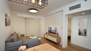A modern living room with a sofa, dining table, and a TV on a cabinet.