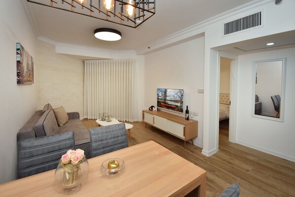 A modern living room with a sofa, dining table, and a TV on a cabinet.
