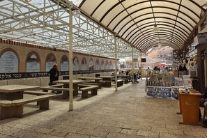 A covered outdoor market with stone benches and vendor stalls. - Boutique Lake Kinneret Apartment (Tiberias)
