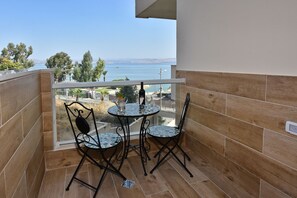 A balcony with a view of the sea, two chairs, and a table. - Boutique Lake Kinneret Apartment (Tiberias)