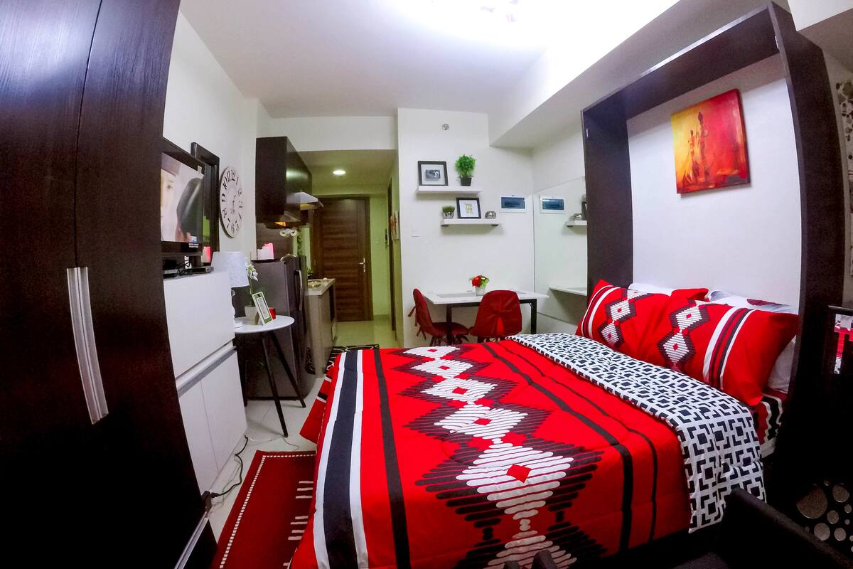 A compact hotel room with a bed, a desk, and a kitchenette.