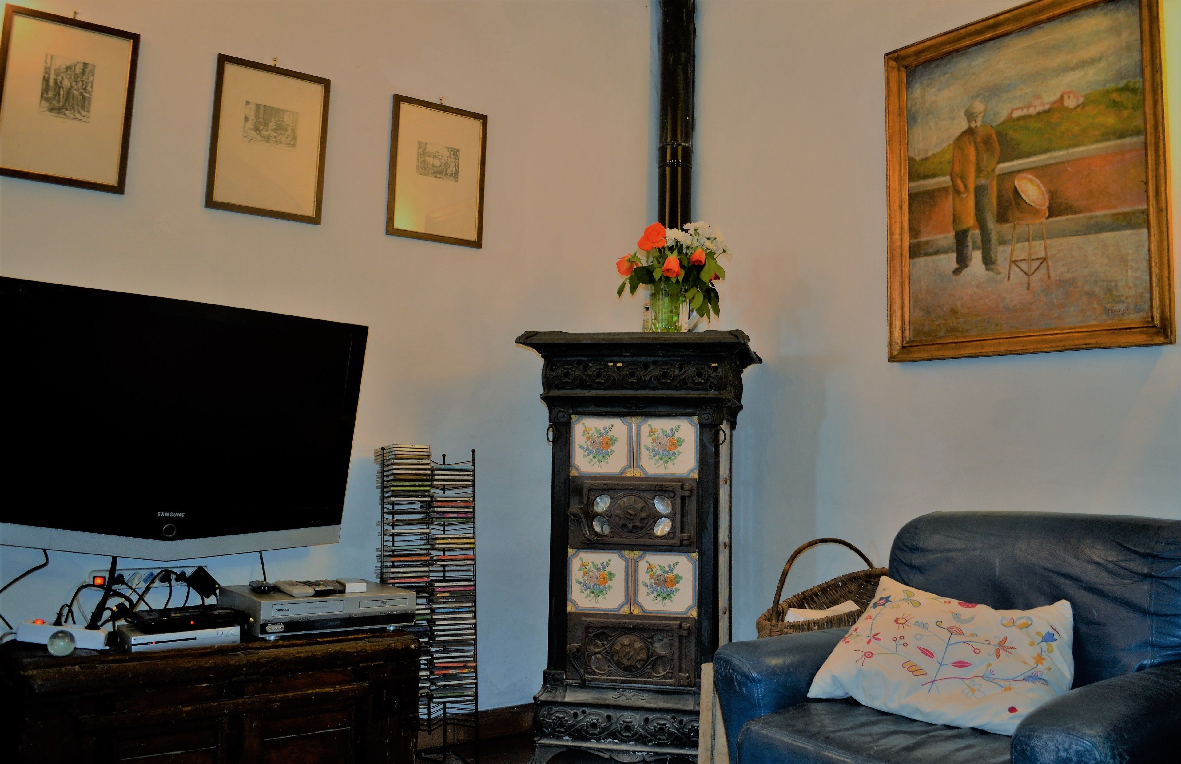 A living room with a television, a fireplace, and a painting on the wall.