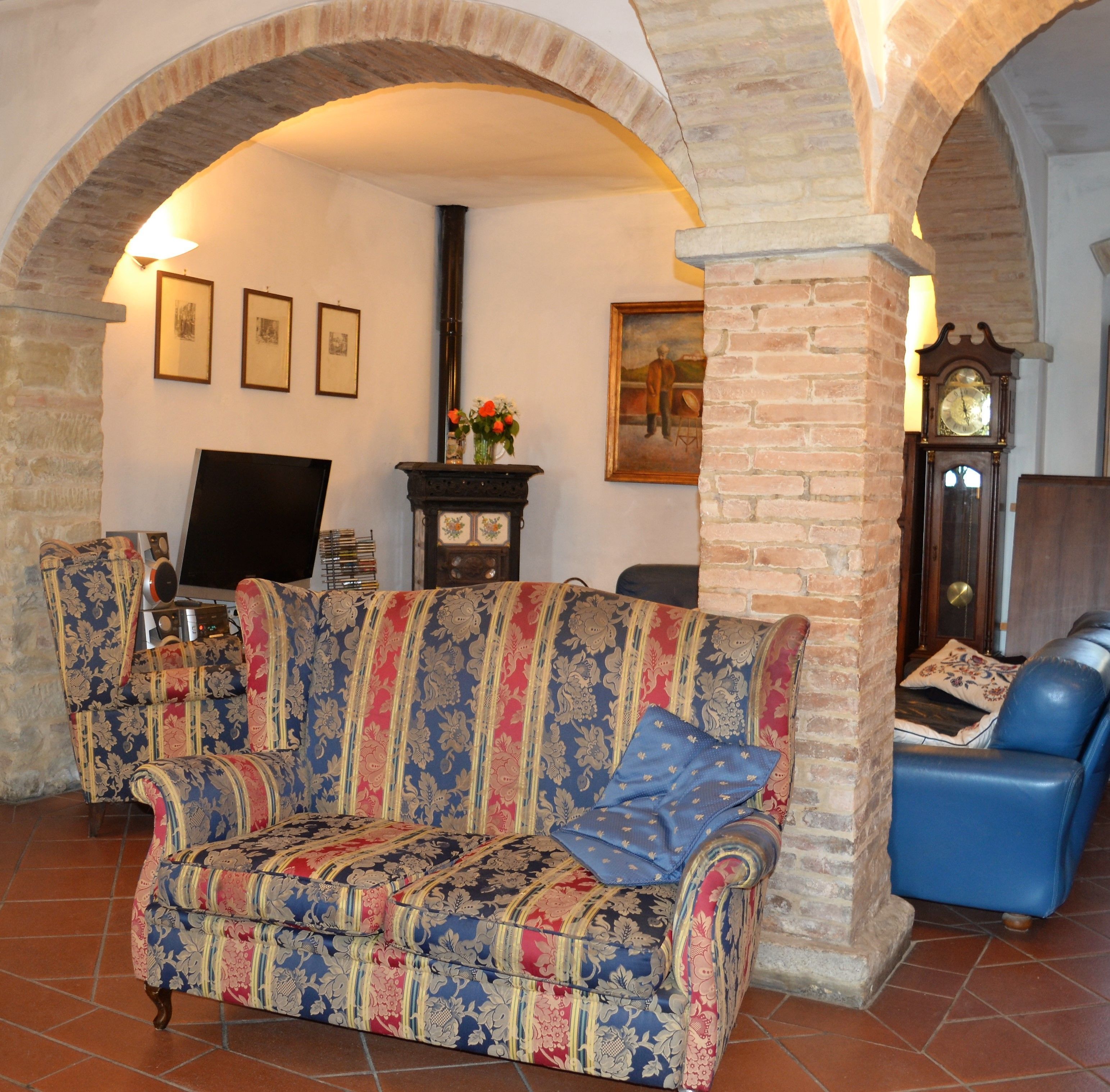 A cozy living room with a patterned sofa, a television, and a clock.