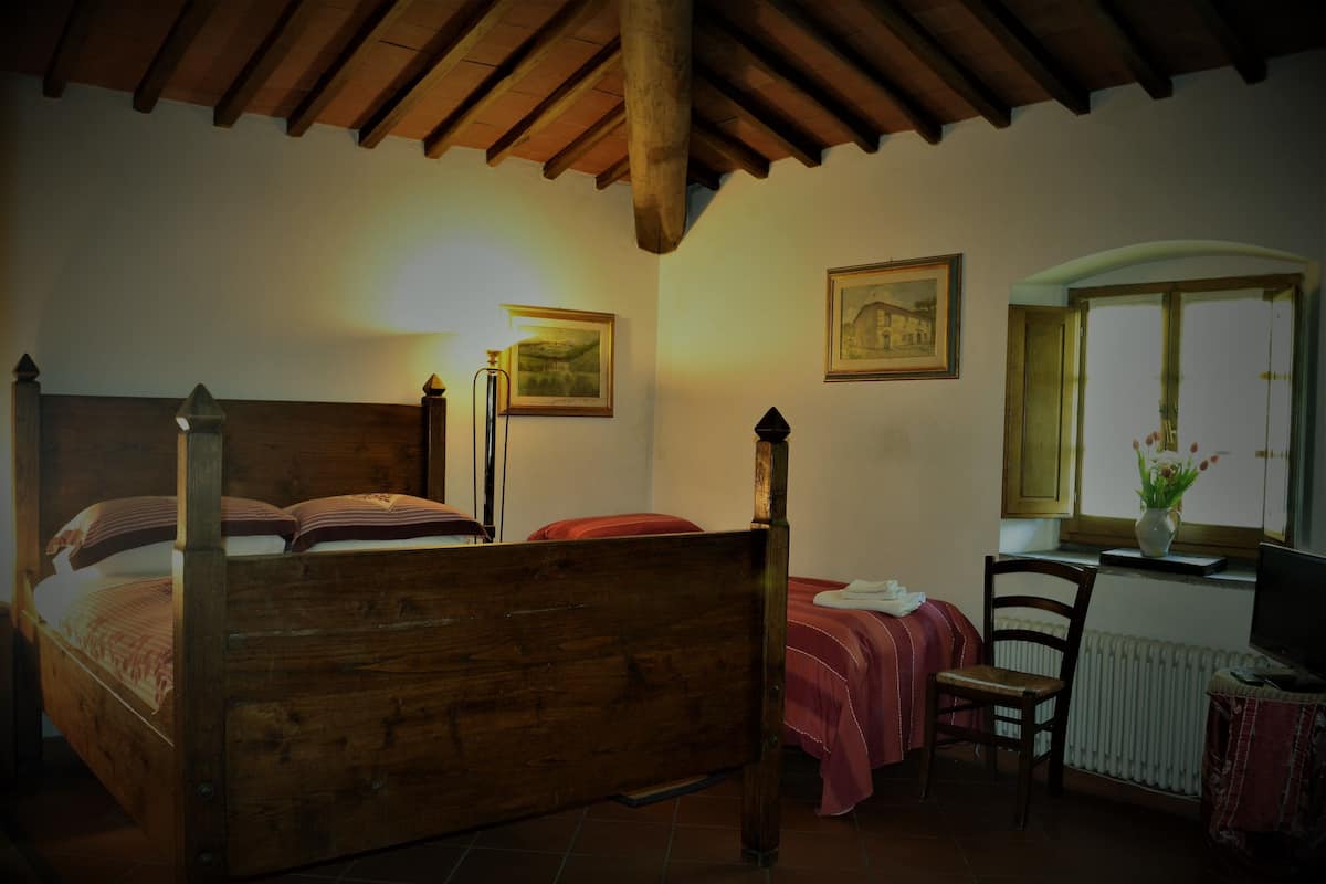 Ein Schlafzimmer mit einem Holzbett, einem Schreibtisch, einem Sessel, einer Heizung und gerahmten Bildern an der Wand.