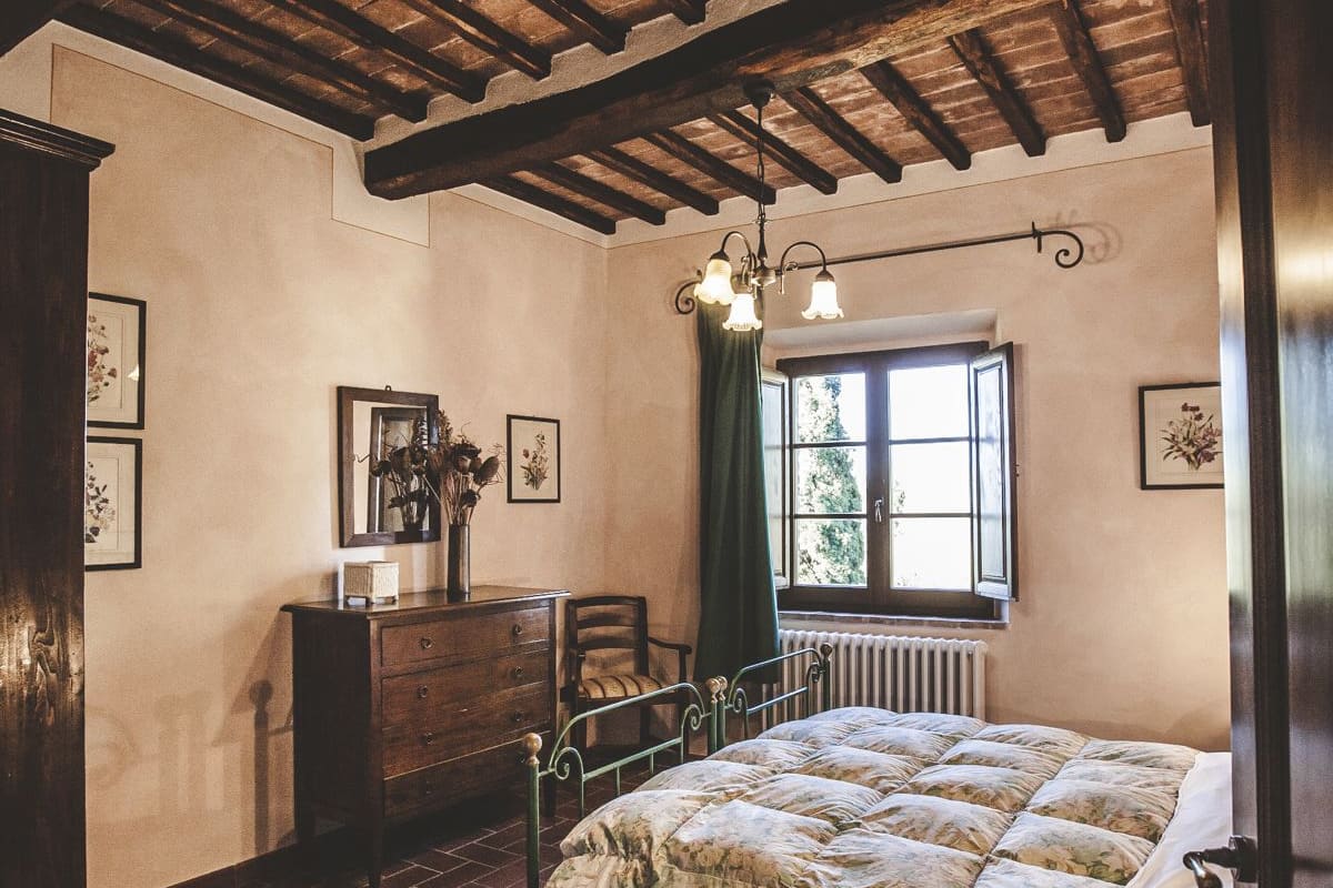 Ein Schlafzimmer mit Holzboden, einem Bett mit Blumenmuster-Bettwäsche, einem Schminktisch und einem Fenster mit Blick.