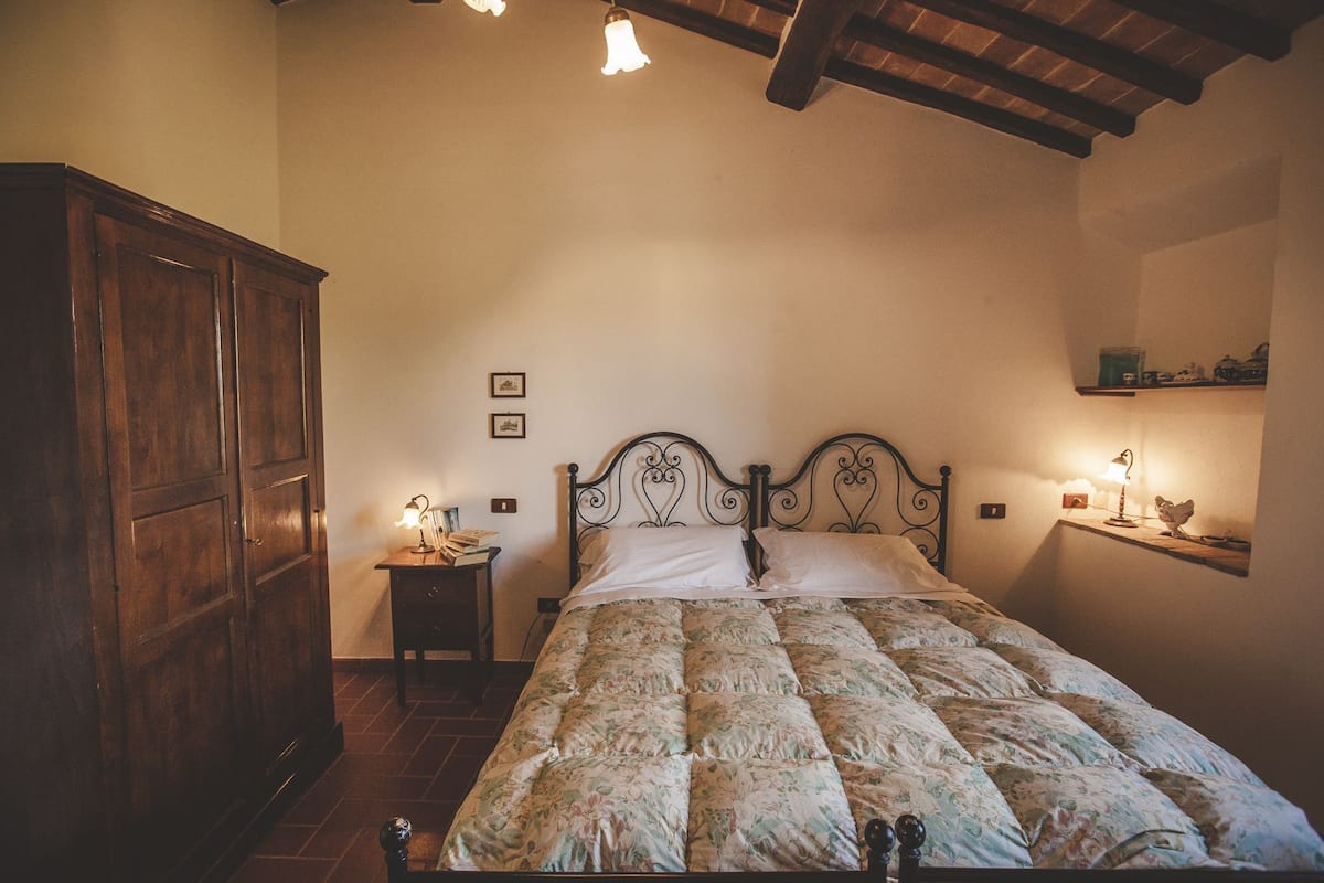 Ein Schlafzimmer mit einem Bett, einem Holzschrank, Nachttischen und einem Regal mit Dekoration.