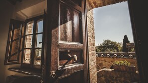 An open wooden door with a view of a stone wall and a potted plant outside. - Zampugna (Trequanda)