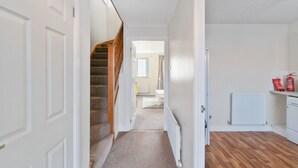 Un couloir avec un escalier recouvert de moquette, un radiateur et un plancher en bois.