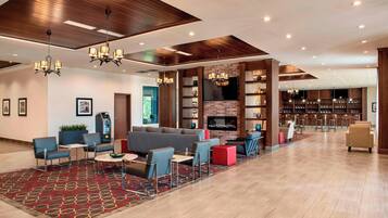 A spacious lobby with a seating area, a fireplace, and a bar/lounge area.