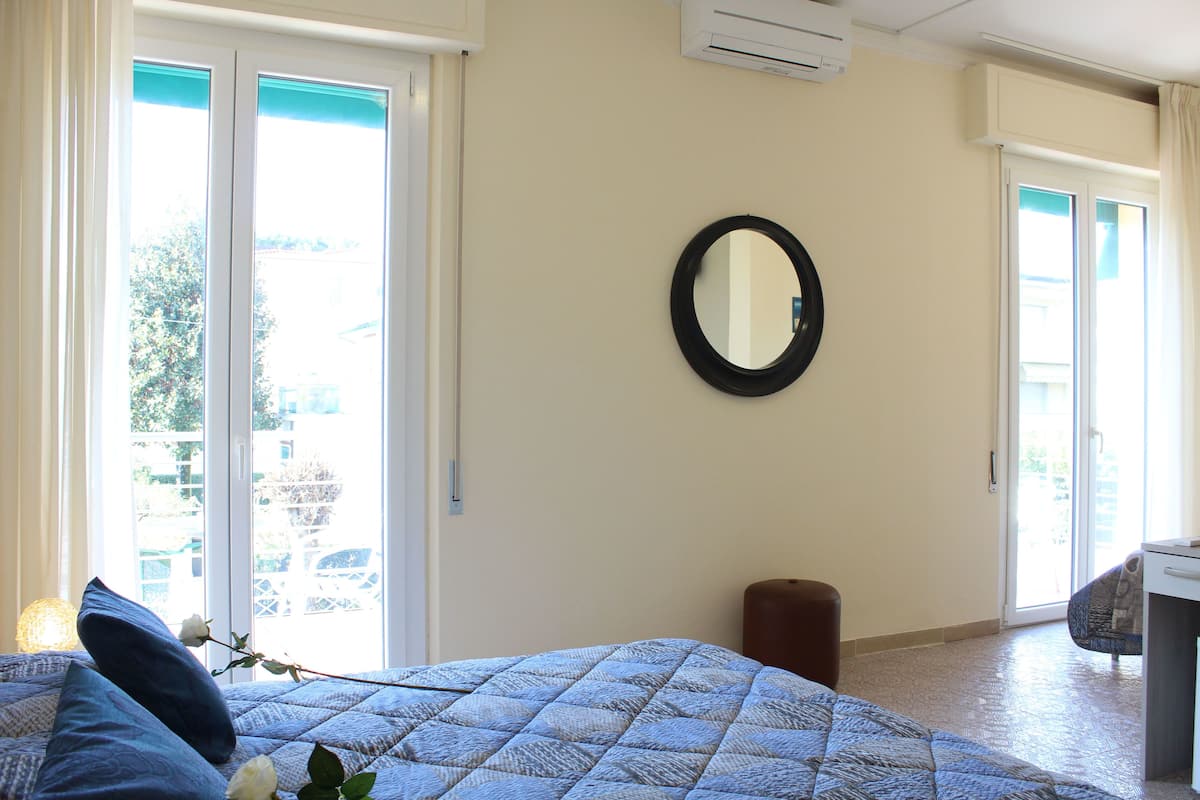 A bedroom with a bed, a round mirror, and a sliding glass door leading to a balcony.