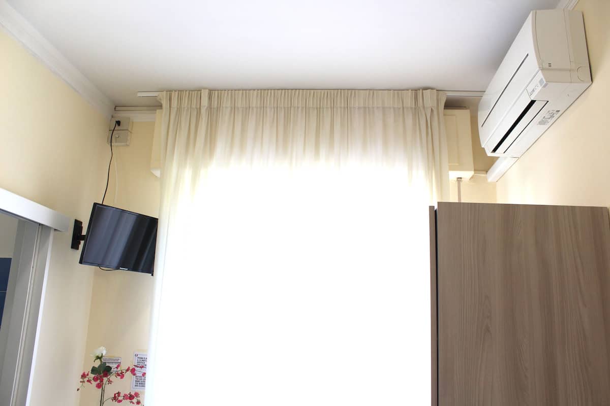 A room with a mounted TV, an air conditioner, and a wooden door.