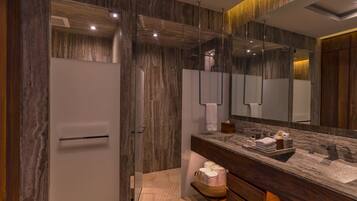 Un baño moderno con un espejo grande, encimera de mármol y zona de ducha.