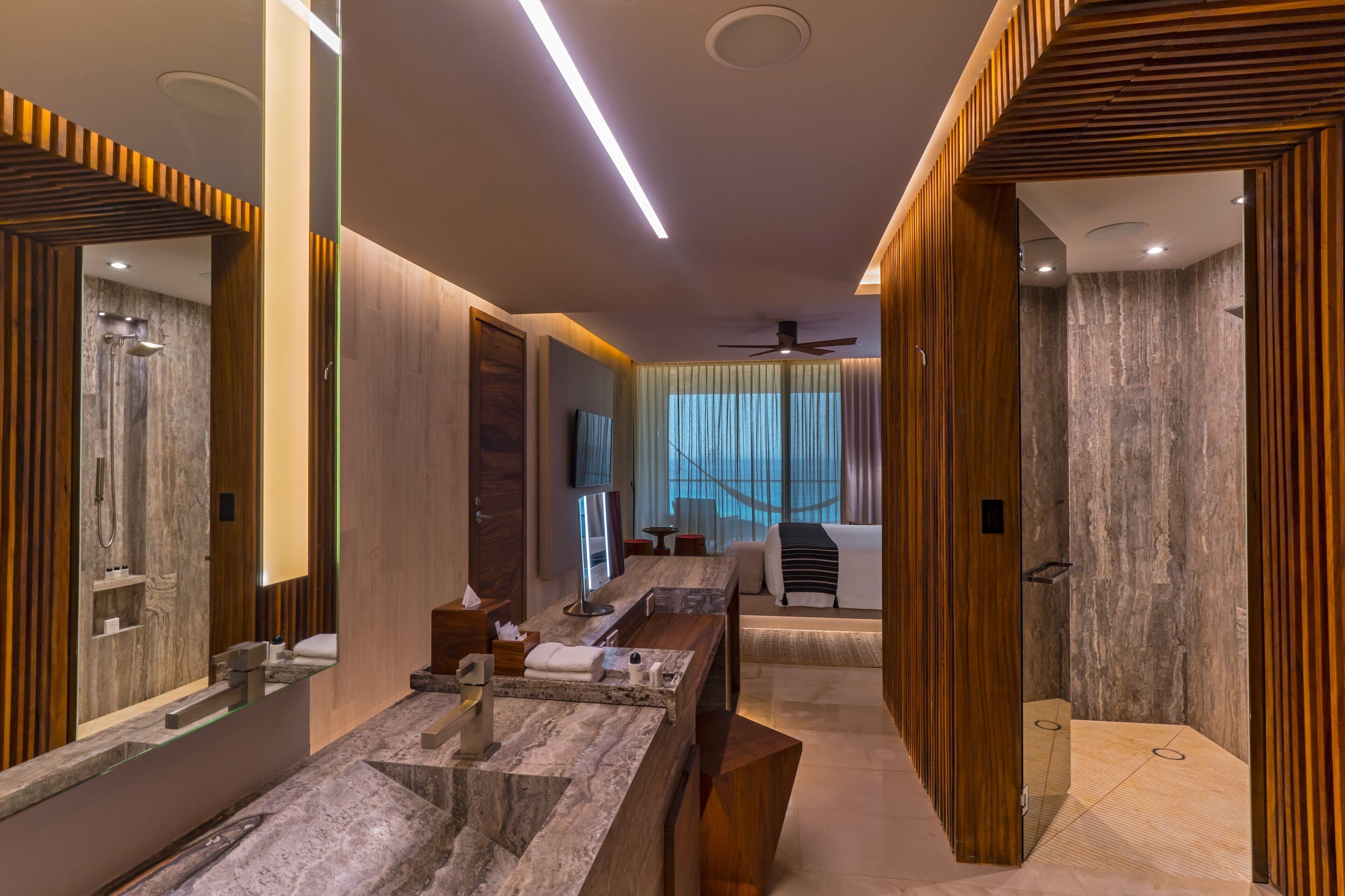 Une salle de bain moderne avec un grand miroir, un meuble-lavabo, une douche et un ventilateur de plafond.