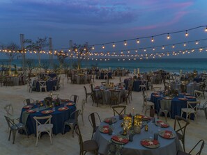 An outdoor dining area with tables set for guests, overlooking the ocean.