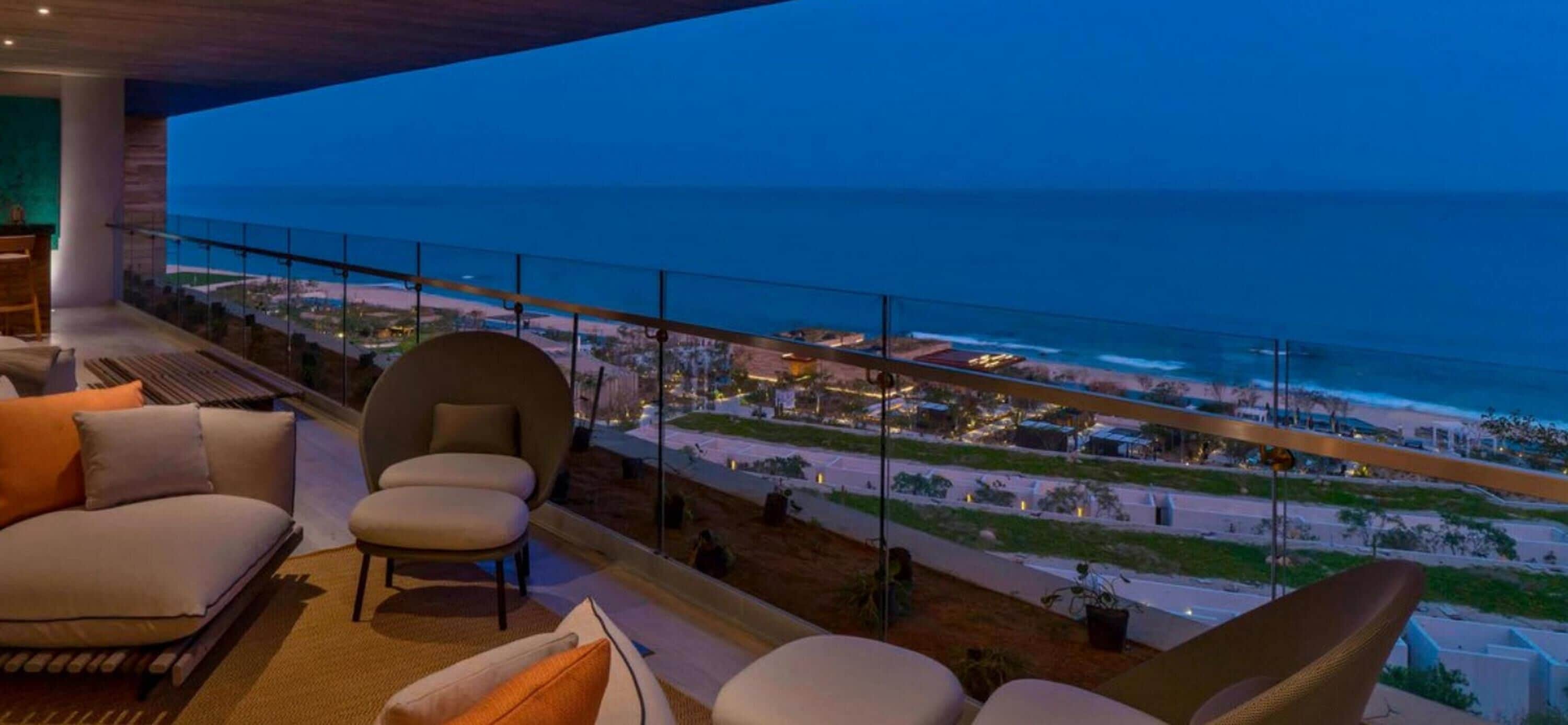 A balcony with a view of the ocean and a cityscape at dusk.