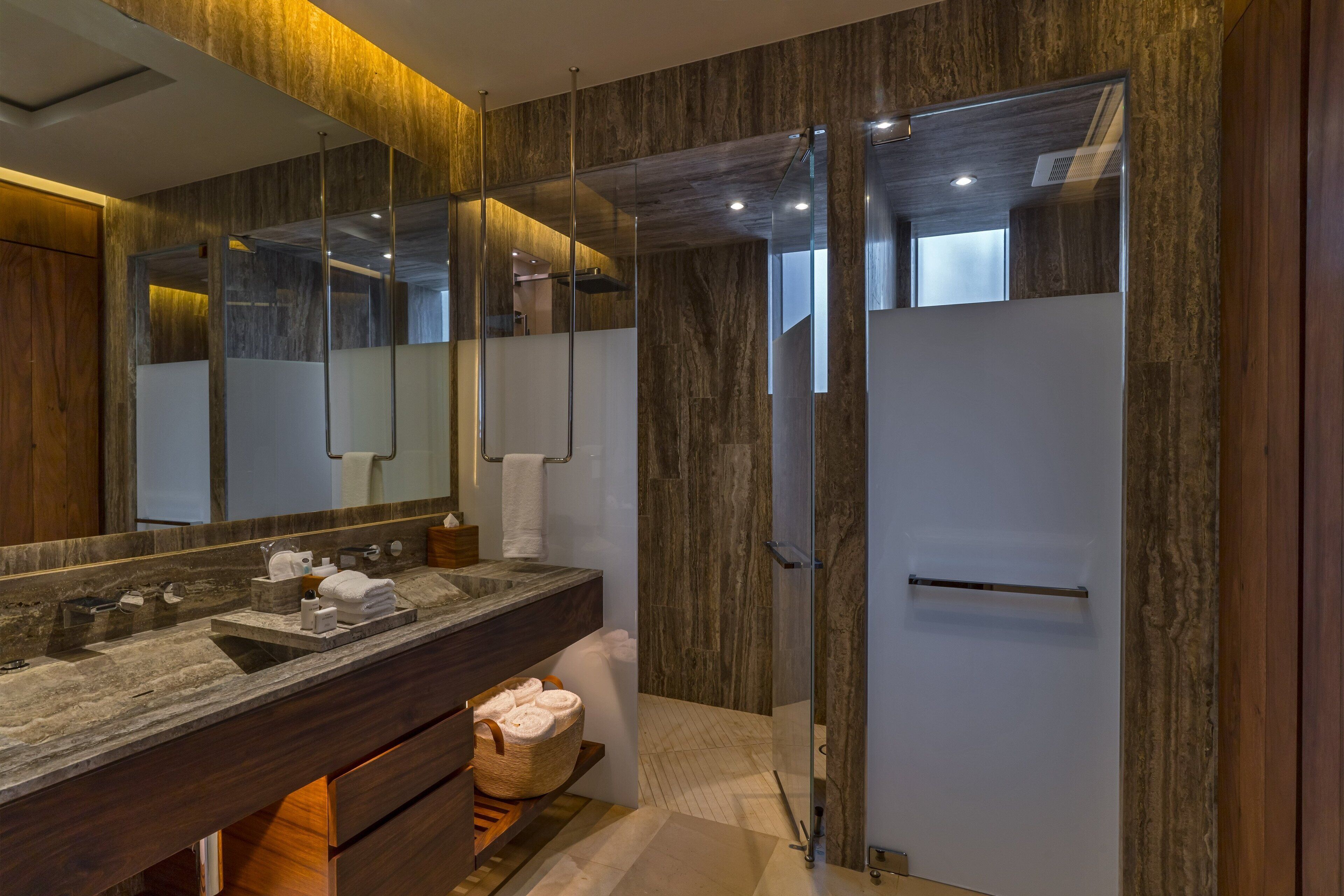 Une salle de bain moderne avec un lavabo en marbre, un grand miroir et une douche à parois de verre.