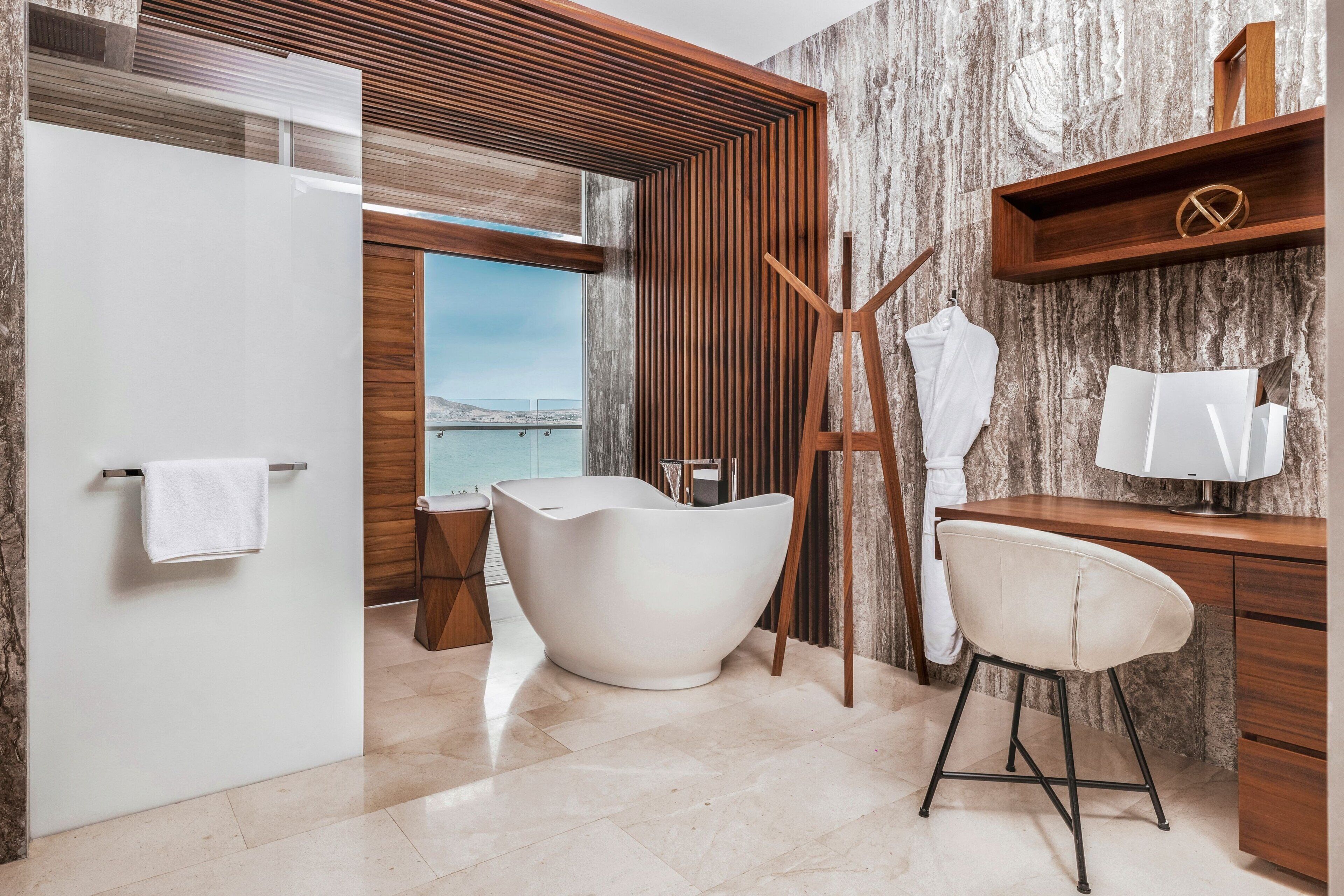 Ein modernes Badezimmer mit einer freistehenden Badewanne, einem Holzbadezimmer-Möbel und einem großen Spiegel.