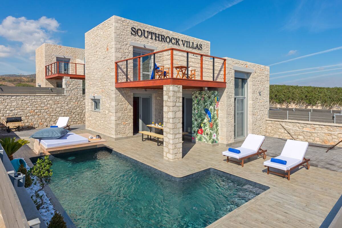A stone building with a pool and lounge chairs.