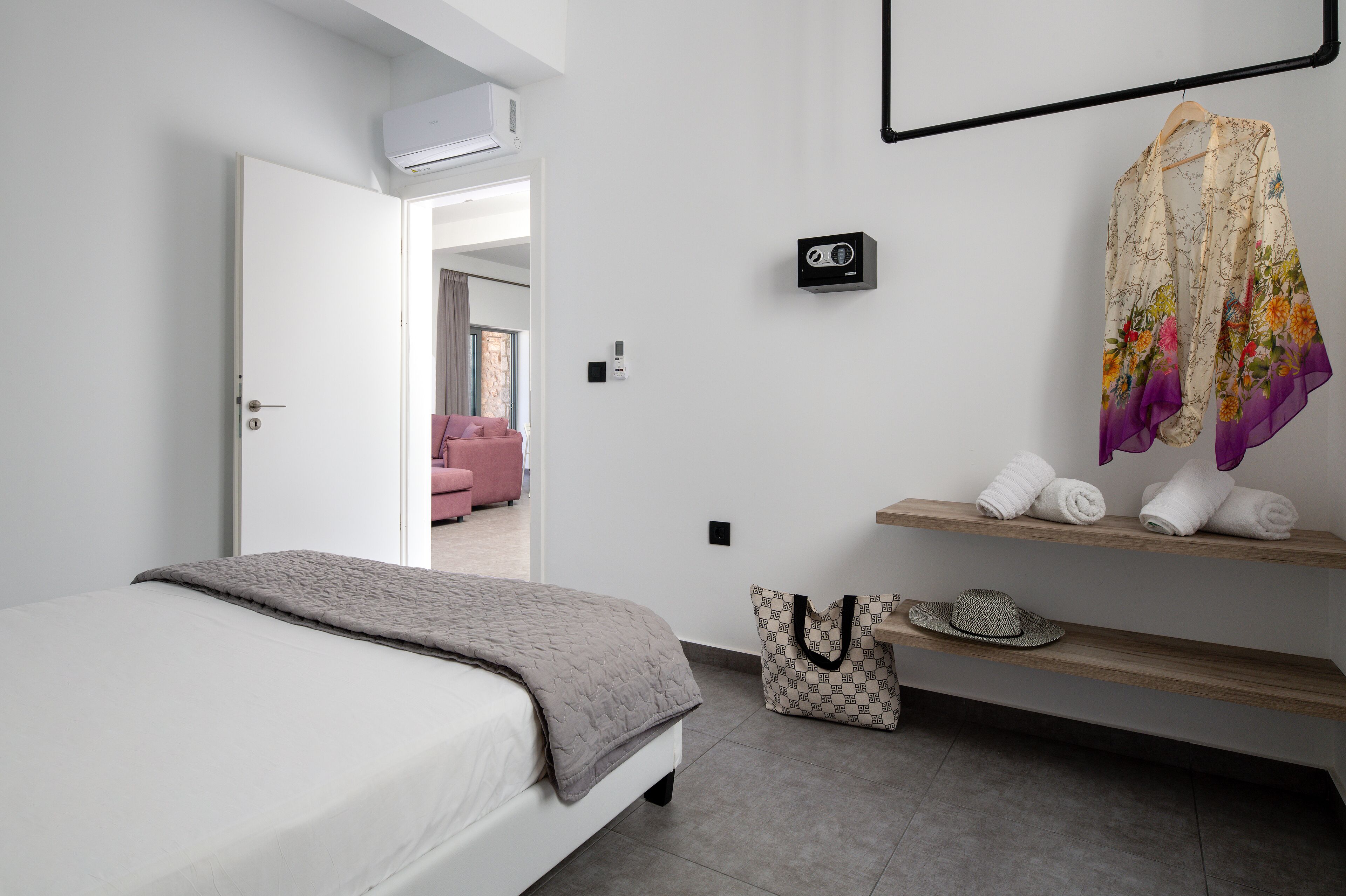 A modern bedroom with a bed, a wardrobe, a vanity with a mirror, and a towel rack.