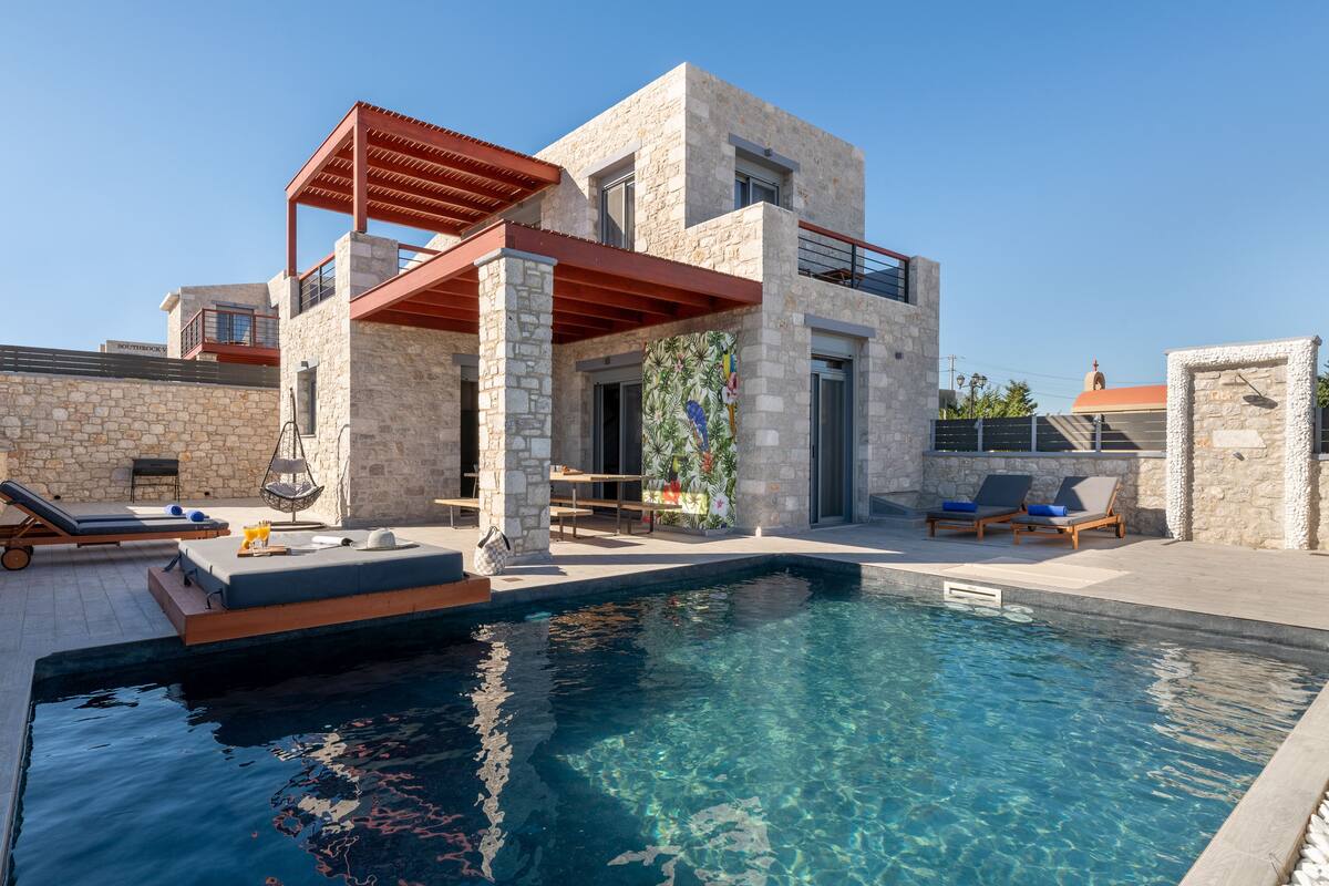 A modern villa with a swimming pool, outdoor seating, and a stone facade.