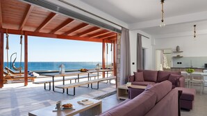 A spacious living area with a large sofa, a dining table, and a view of the ocean. - Southrock Villas (Rhodes)