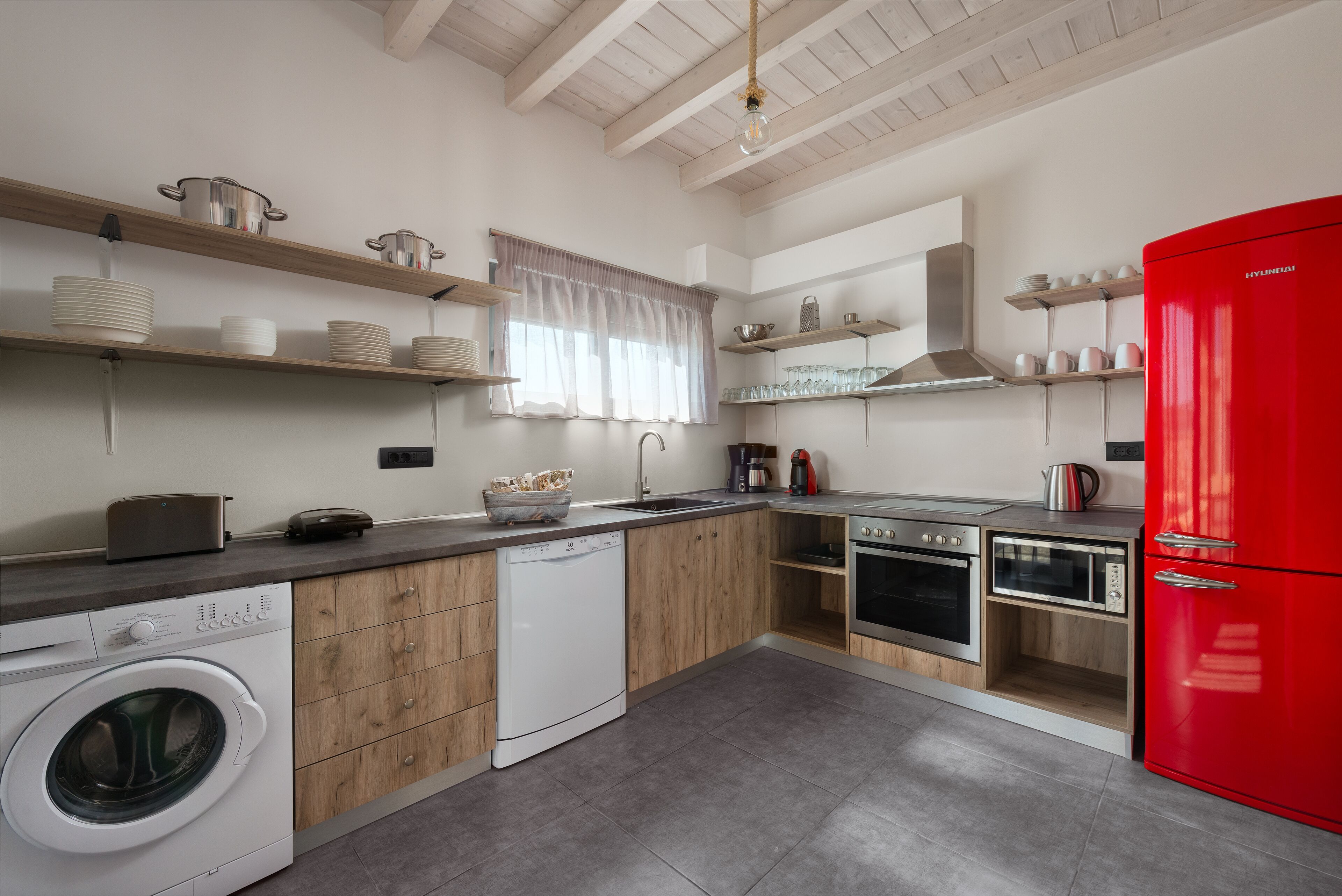 Une cuisine moderne avec des meubles en bois, un réfrigérateur rouge et des appareils électroménagers en acier inoxydable.