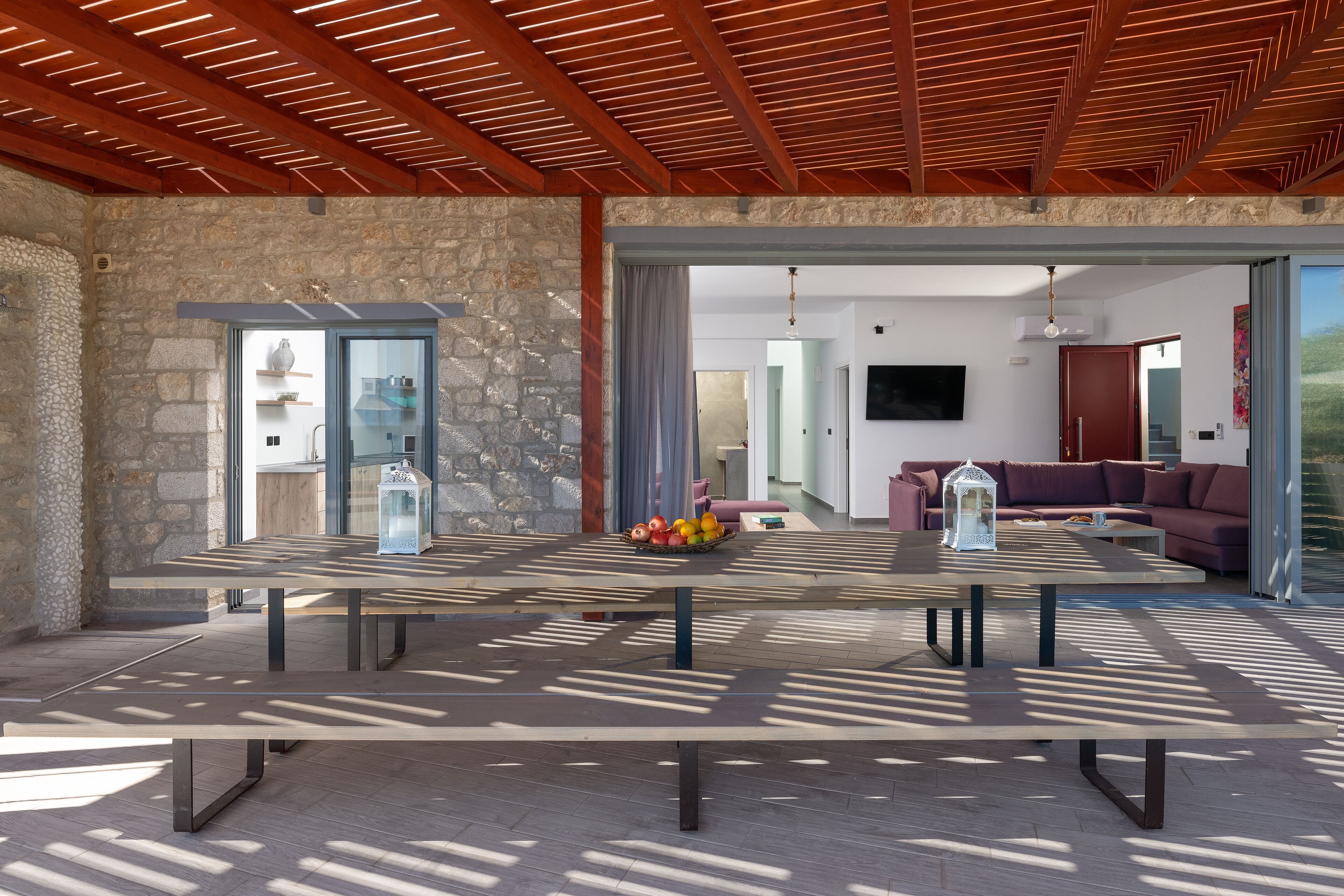 Un'ampia stanza con soffitto in legno, pareti in pietra e un grande tavolo con una ciotola di frutta.