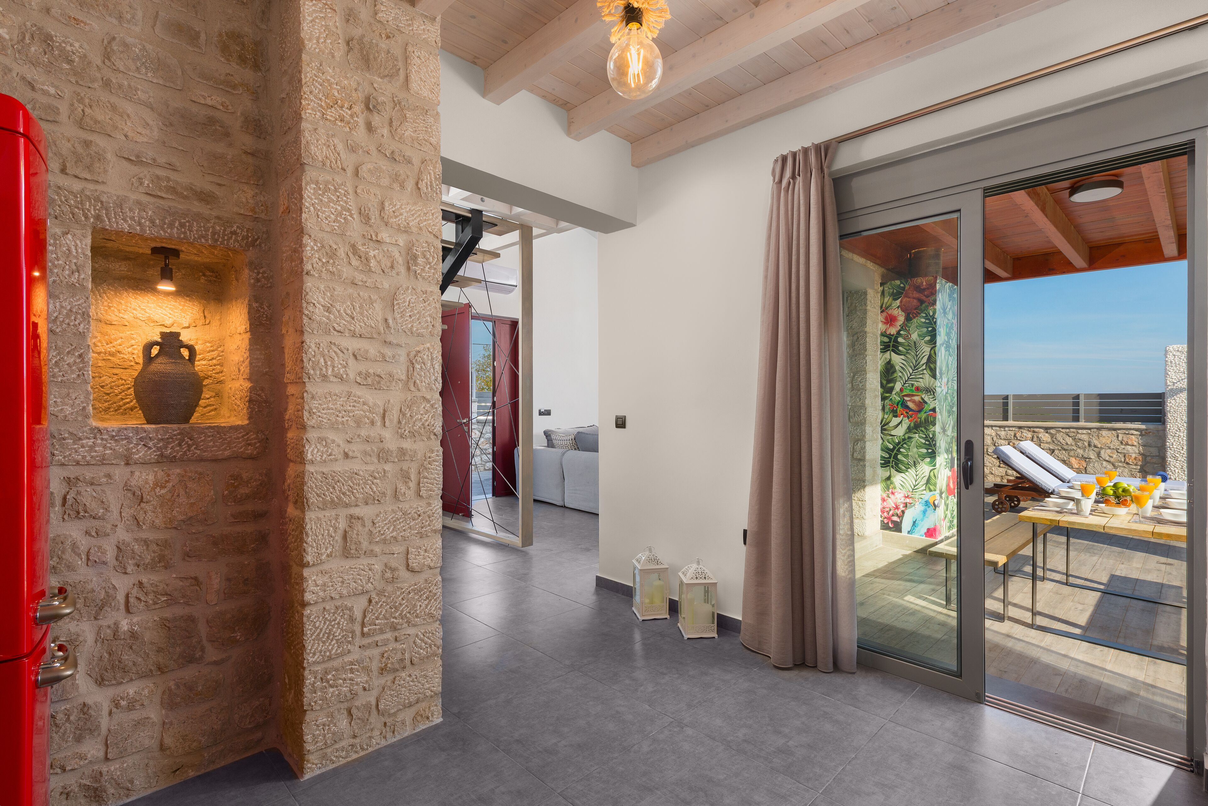 Un intérieur moderne avec des murs en pierre, un meuble rouge et un balcon offrant une vue imprenable.