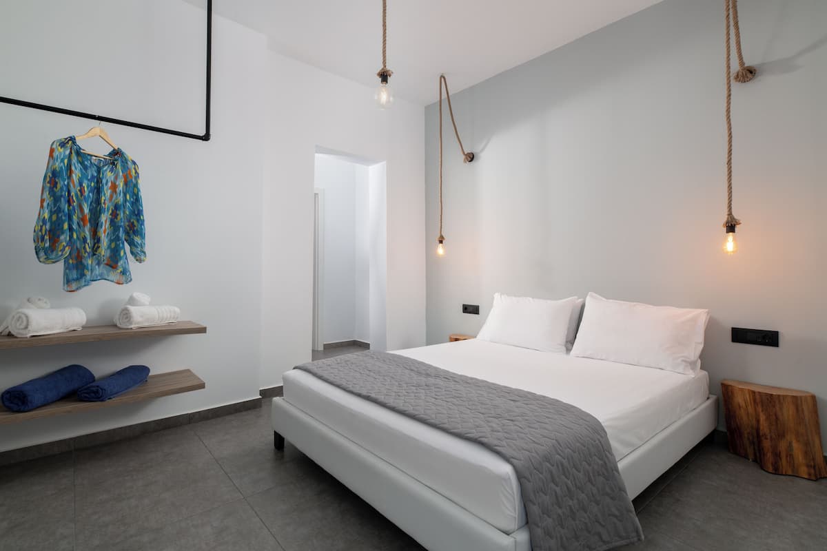 Une chambre moderne avec un grand lit, des étagères en bois et un luminaire suspendu.