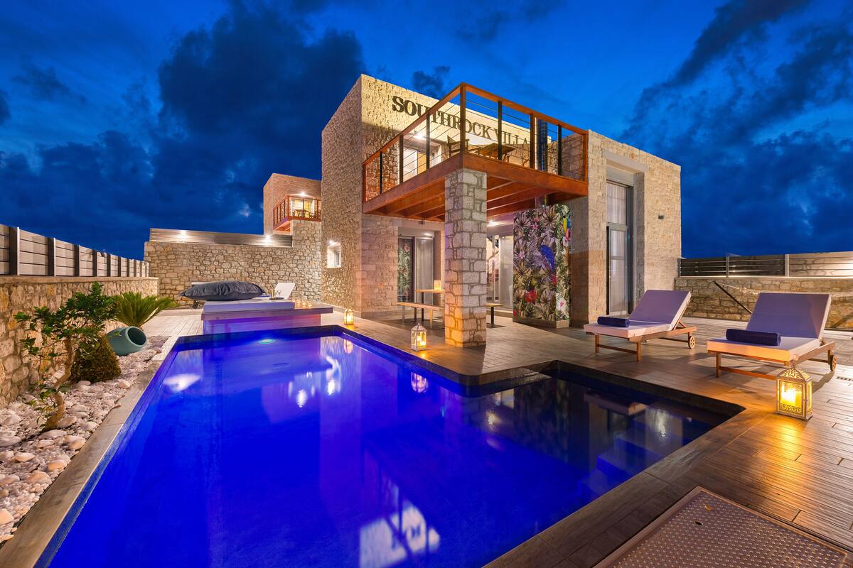 A modern poolside area with a stone facade, lounge chairs, and a clear pool.