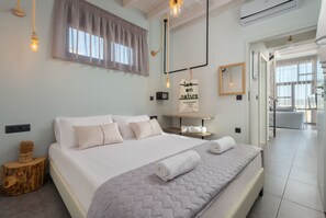 Une chambre d’hôtel moderne avec un grand lit, une table de chevet, un miroir et une vue sur le couloir.