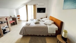 Ein Hotelzimmer mit Bett, Schreibtisch, Stuhl, Fernseher und einem Bild an der Wand.