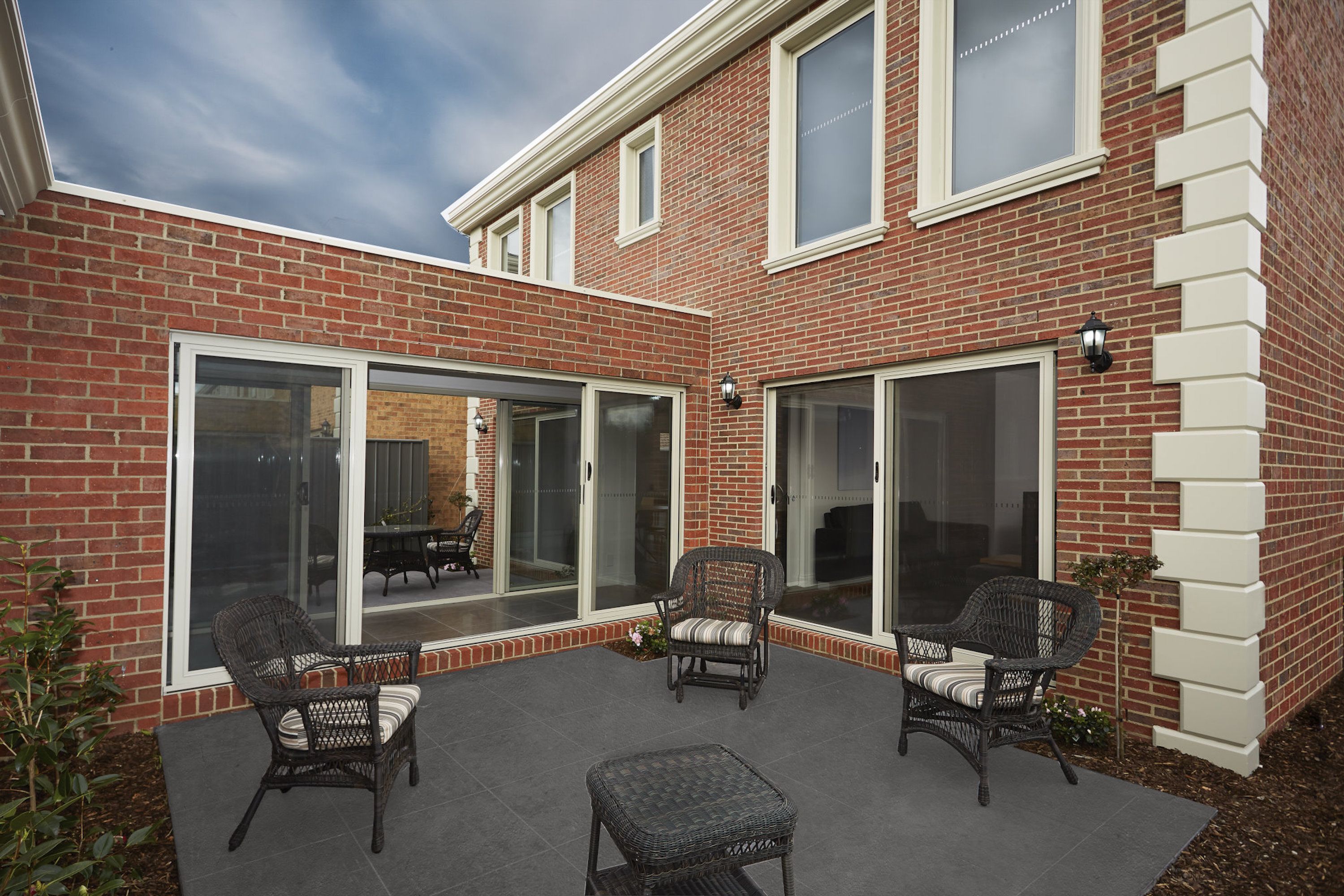 Un espace patio aménagé avec des meubles en osier et une maison en briques.