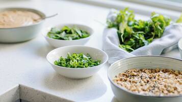 Una encimera de cocina con recipientes que contienen verduras, frutos secos y una sustancia cremosa.