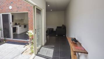 A modern kitchen with sliding doors, a dining area with a sofa, and a wooden table with a red object.