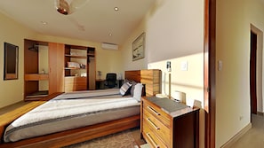 Een slaapkamer met een bed, een houten kledingkast, nachtkastje en een bureau met stoel.