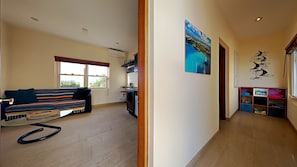 Een ruime woonkamer met een bank, een keuken en een gang naar een slaapkamer.