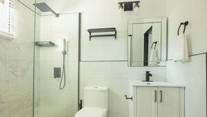 A modern bathroom with a glass-enclosed shower, a toilet, and a vanity with cabinets. - Furnished 1 bedroom Apartment in Gated Complex  (Kingston)