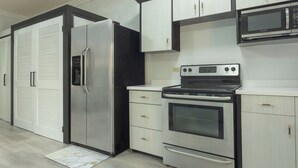 A kitchen with a stainless steel refrigerator, a built-in oven, and a microwave. - Furnished 1 bedroom Apartment in Gated Complex  (Kingston)