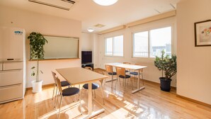 A conference room with a large table, chairs, a whiteboard, a television, and potted plants. - All In Stay Hakodate (Hakodate)