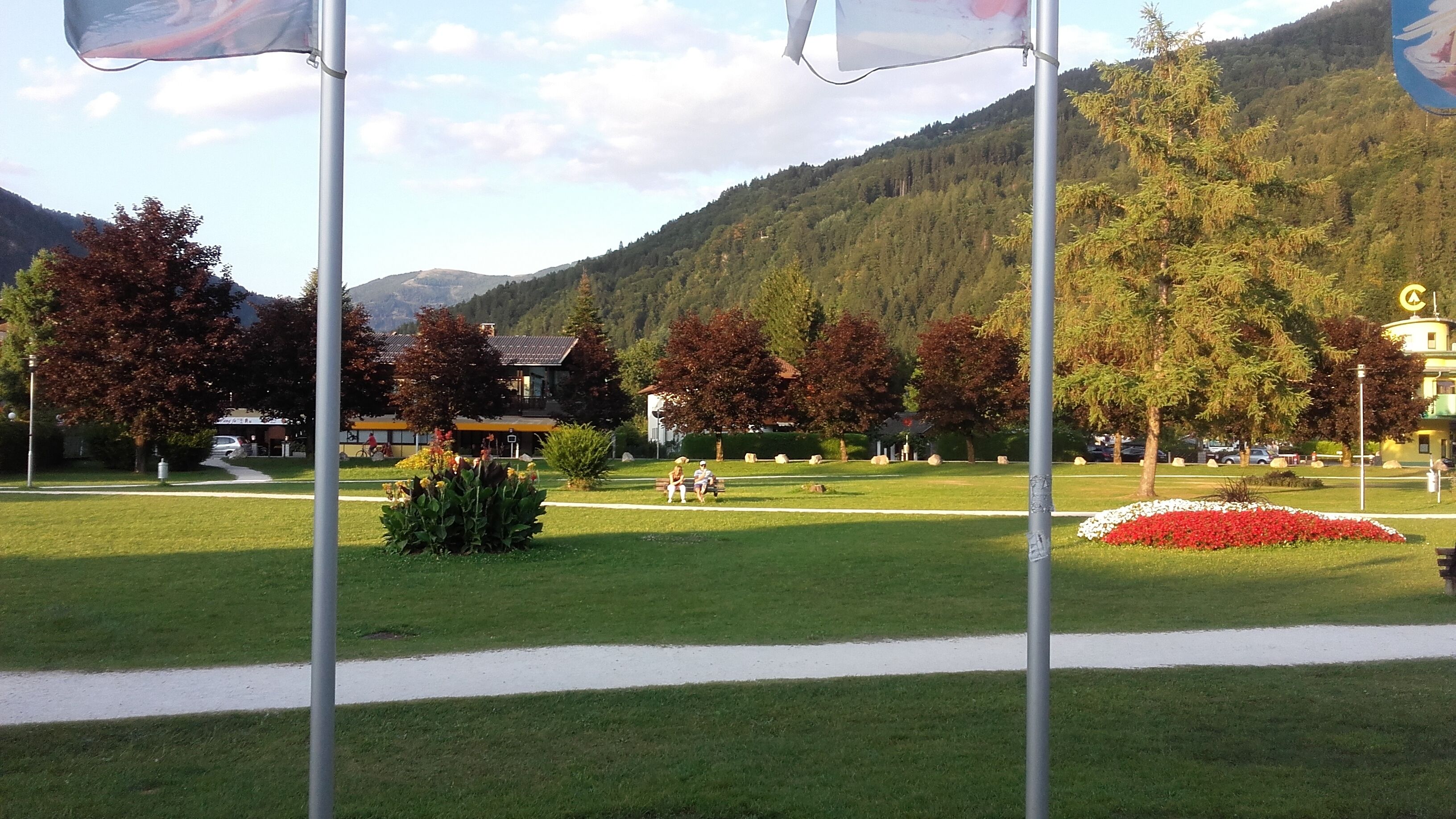 Un parque con césped, bancos y un edificio al fondo.