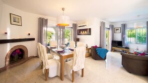 Een goed verlichte woonkamer met een eetgedeelte, een open haard en een televisie.