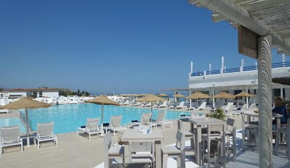 Relax by the pool surrounded by lounge chairs and umbrellas under a covered area with a railing.